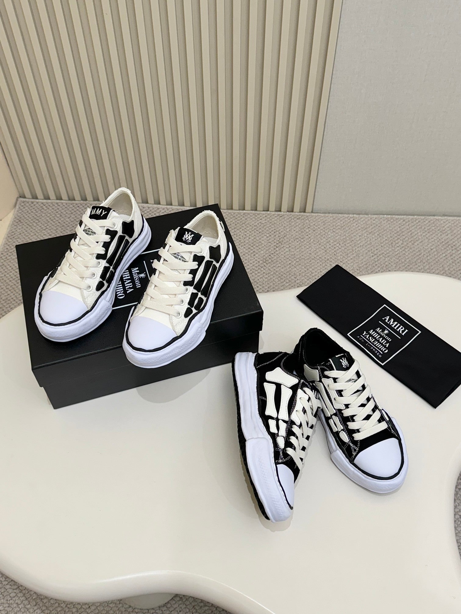 Pair of black and white lace-up sneakers on shoebox, one front and one side visible