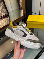 Fendi unisex lace-up sneakers held in hand, white and gray with yellow eyelet accents