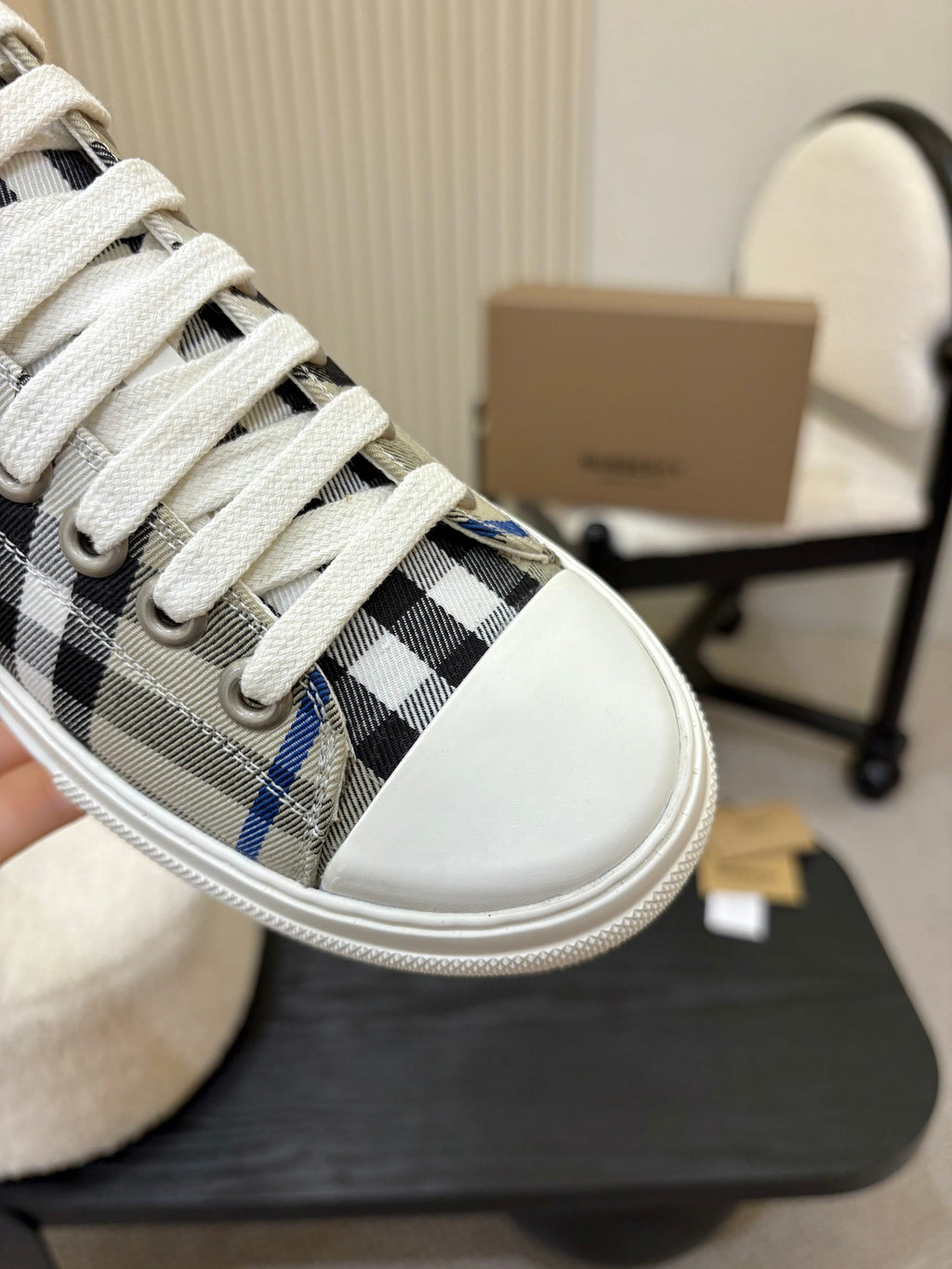 Burberry sneaker close-up, white laces over black and blue check fabric upper