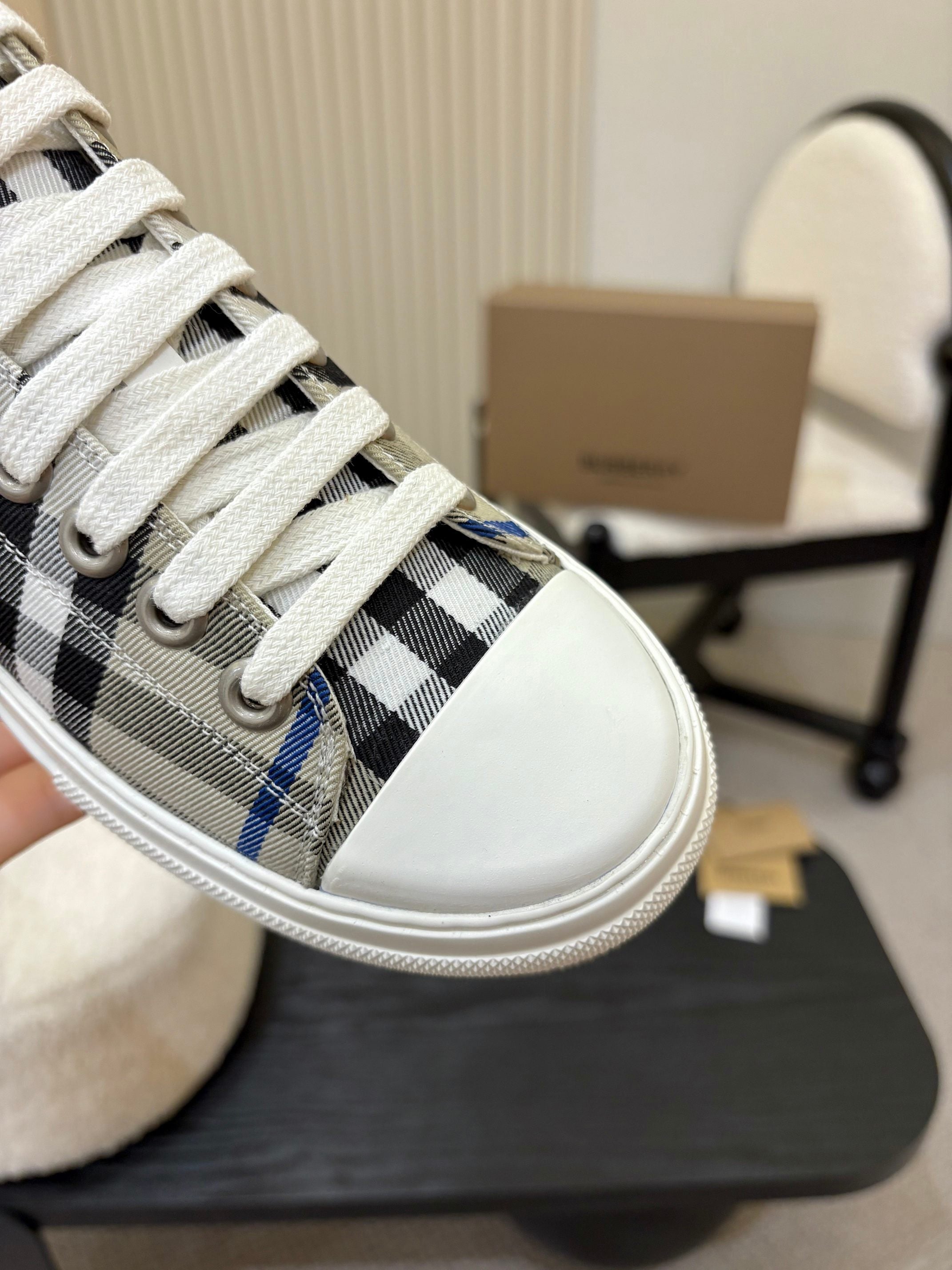 Burberry sneaker close-up, white laces over black and blue check fabric upper