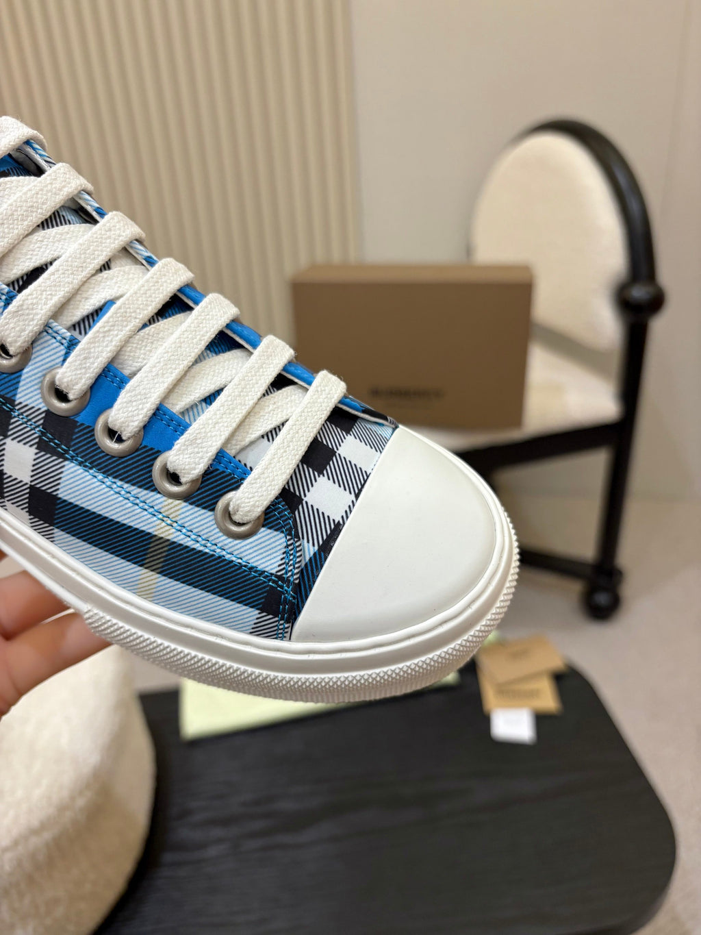 Burberry sneaker close-up: blue and white plaid fabric with white lace stitching