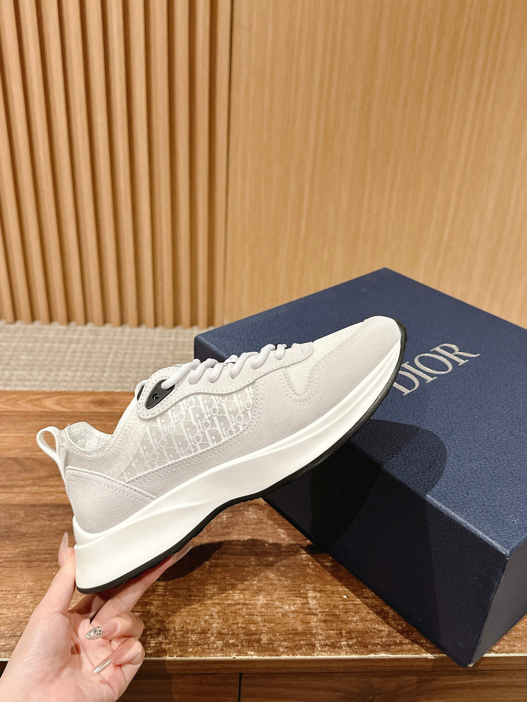 White Dior sneakers in side profile, textured upper and white rubber sole
