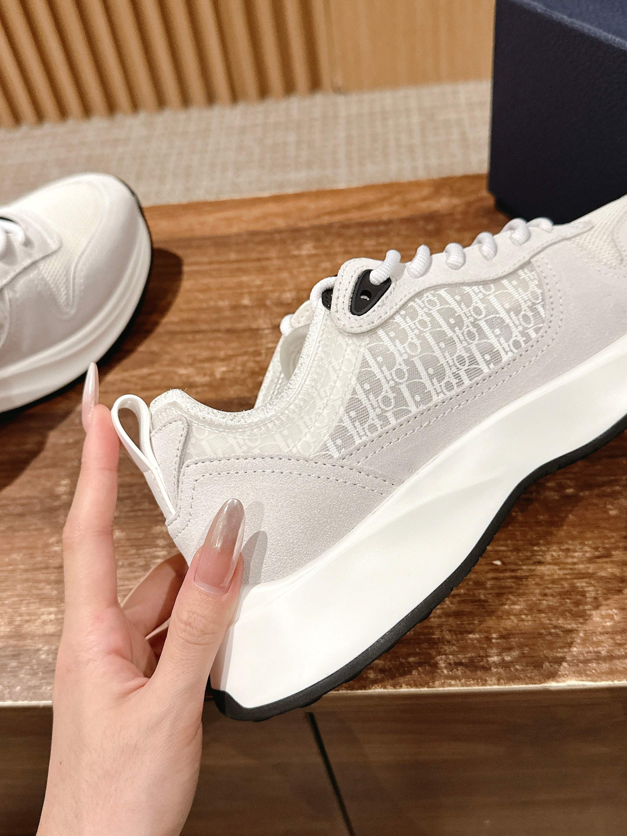 White Dior sneaker on wooden stand, lace-up with patterned side panel