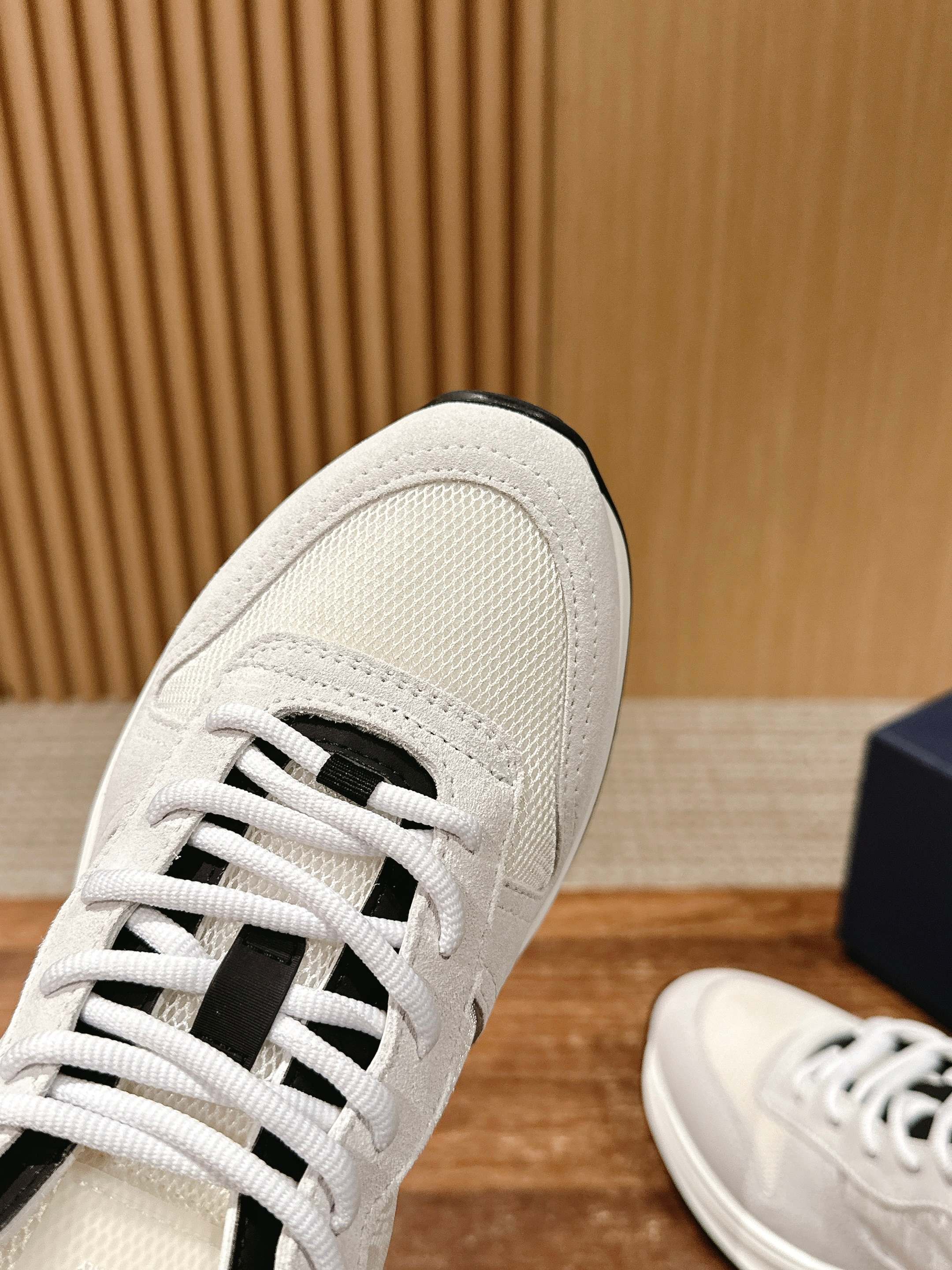 White Dior sneaker upper close-up, embossed texture and black D detail