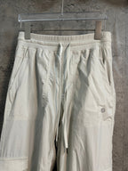 White cargo pants with elastic waistband, drawstring ties, and side panel pockets