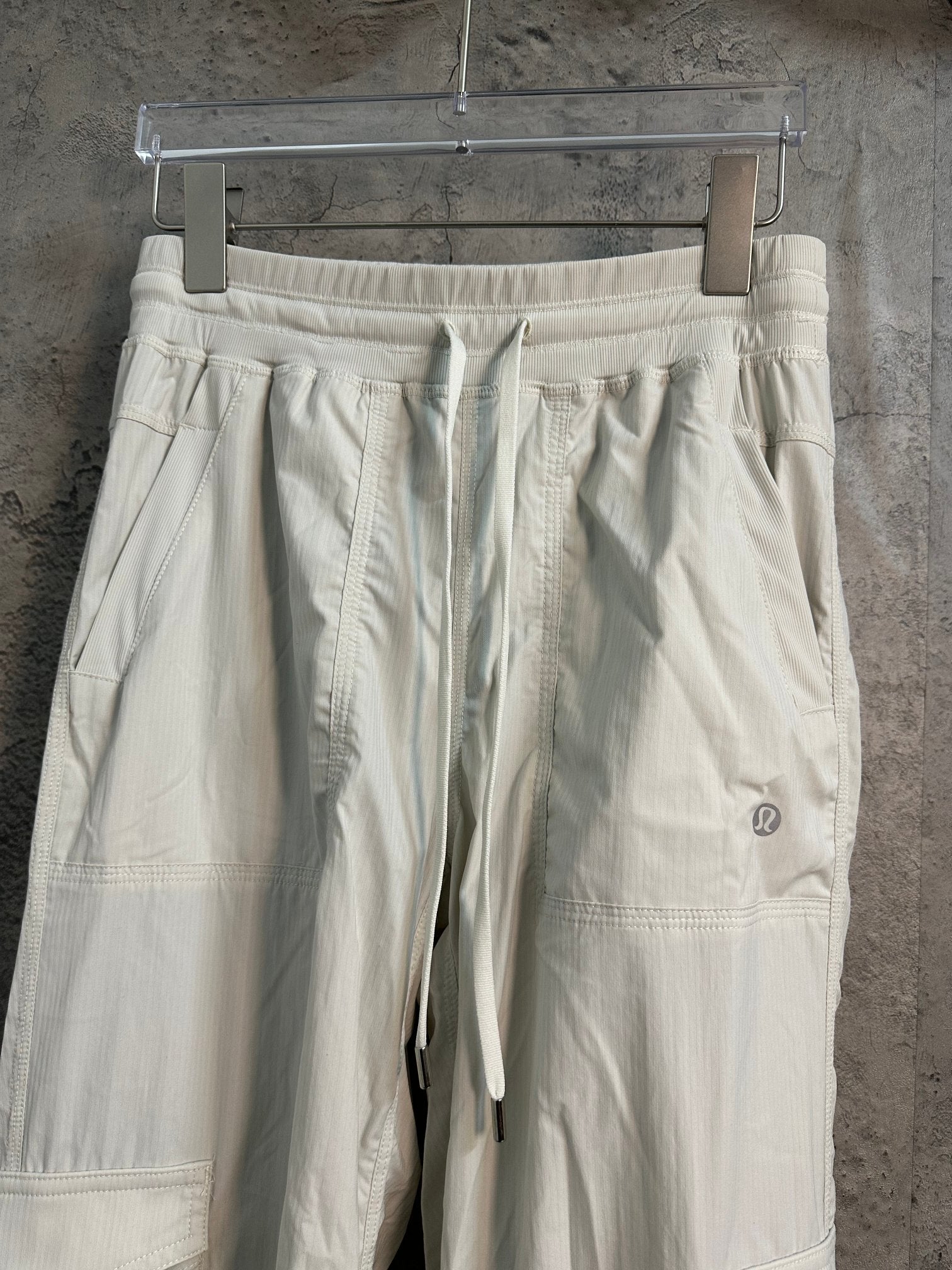 White cargo pants with elastic waistband, drawstring ties, and side panel pockets