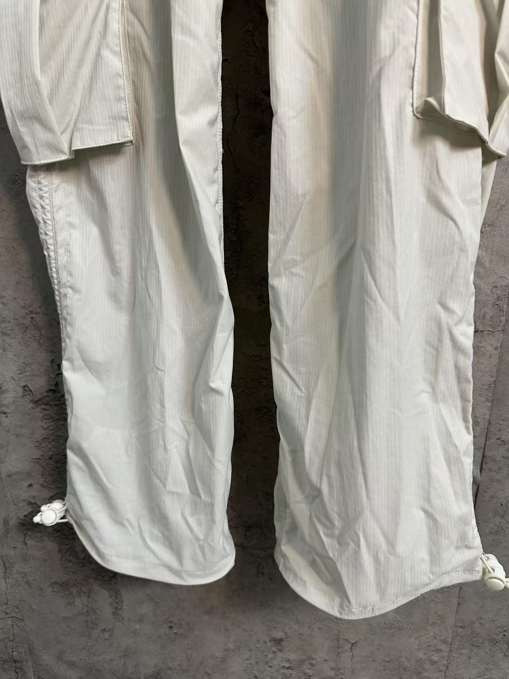 White cargo pants with tapered legs and buttoned hem cuffs