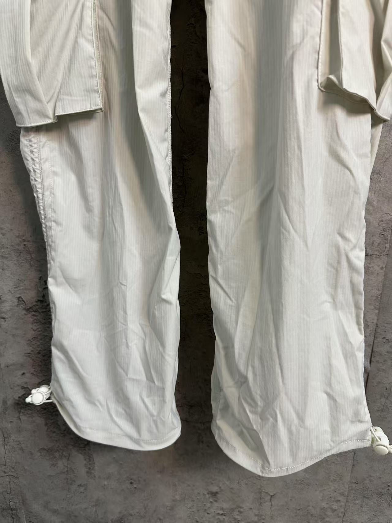 White cargo pants with wide legs and side hem ties