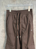 Dark brown cargo pants close-up showing waistband, drawstring ties, and side pockets