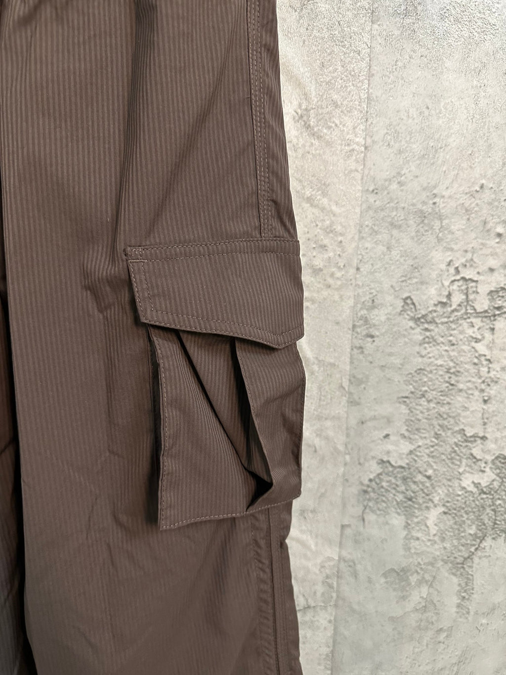 Dark brown cargo pants with layered side panel and utility pocket at hem