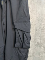 Black cargo pants close-up with flap pocket and pleated fabric