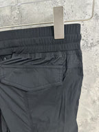Black cargo pants detail: ribbed waistband and buttoned flap pocket