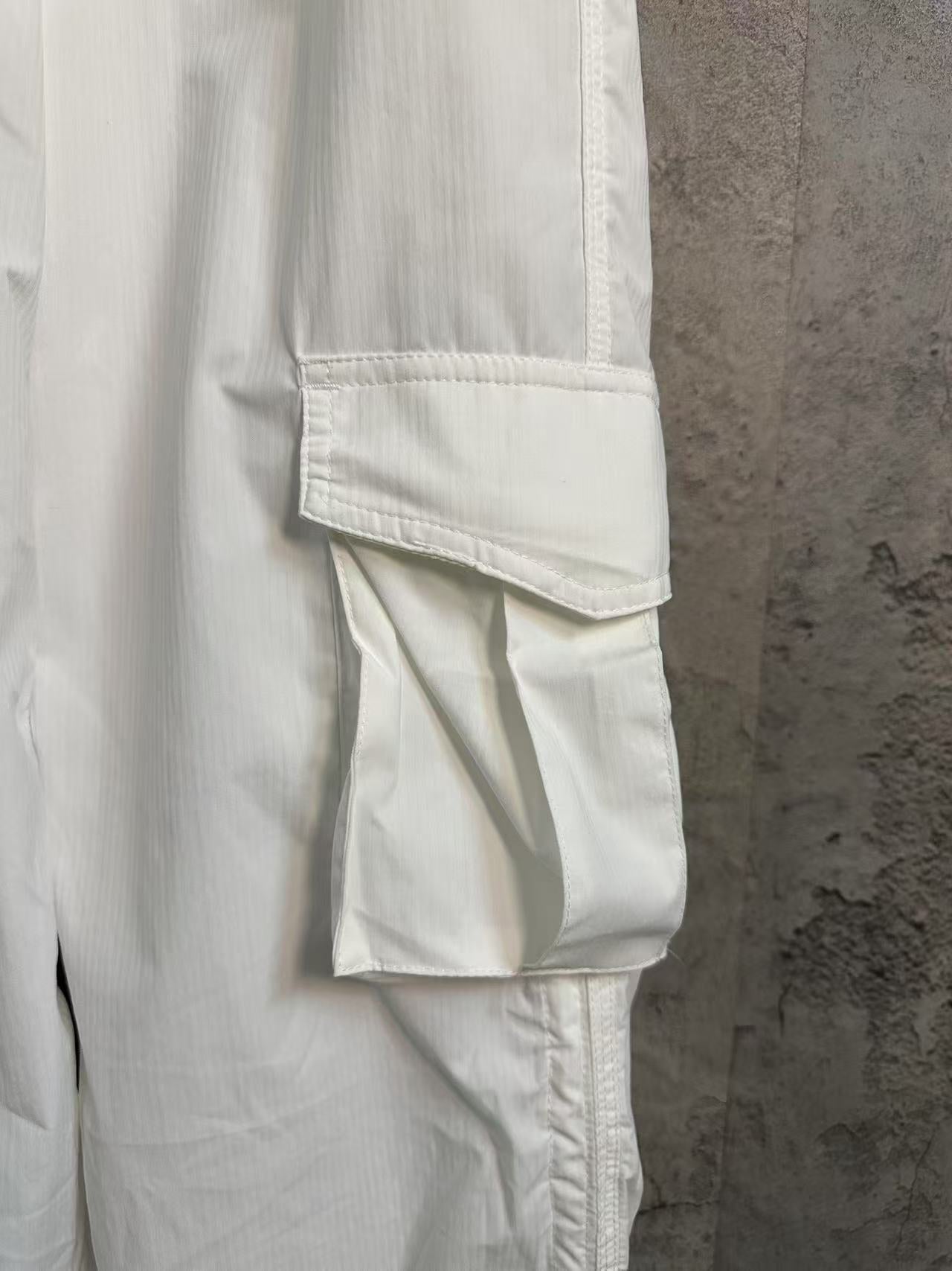 White cargo pants with layered cargo pocket detail and zipper-free side seam