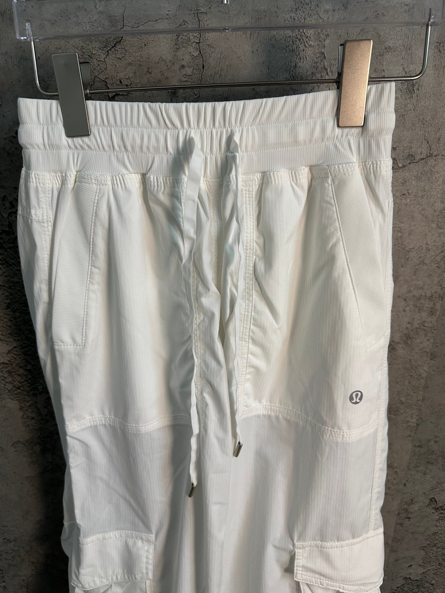 White cargo pants with elastic waistband, drawcord, and side pockets on thigh