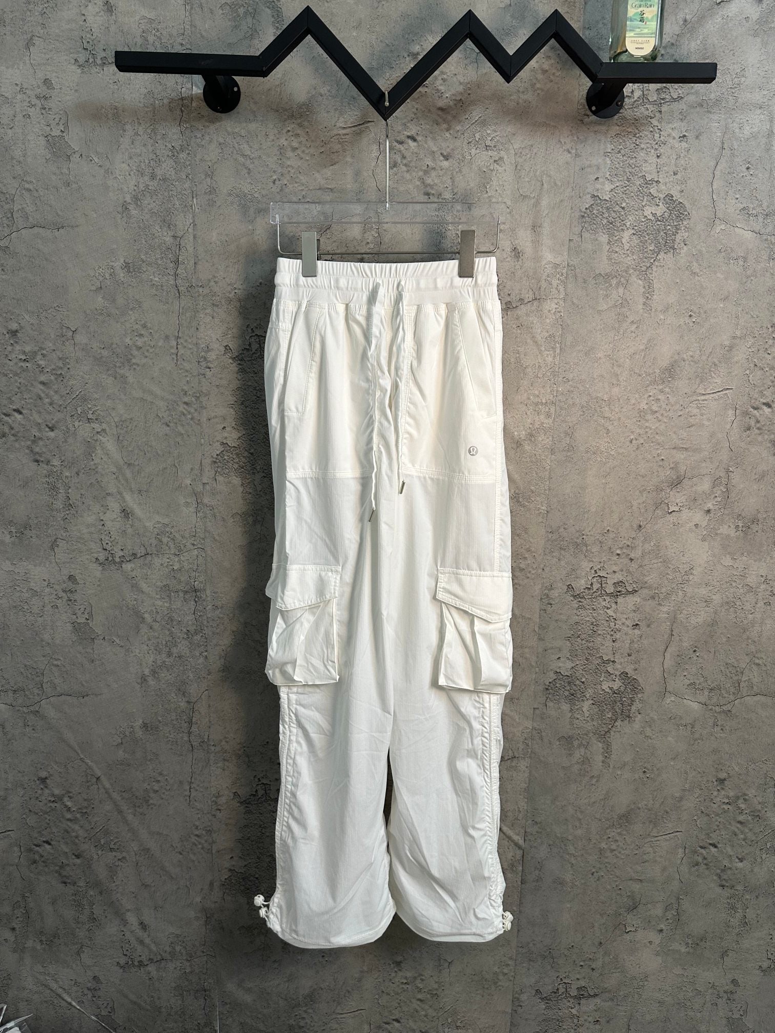 White cargo pants with drawstring waist, cuffed legs, and large utility pockets