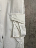 White cargo pants with cargo pocket flap and seam detail, side close-up