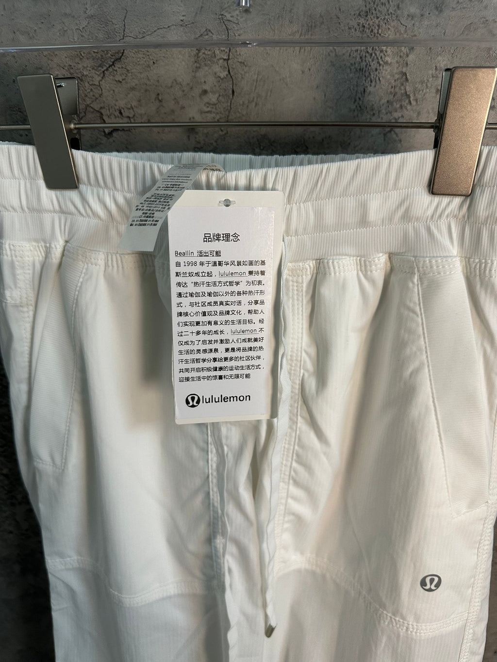 White cargo pants with attached care label and side pocket on thigh