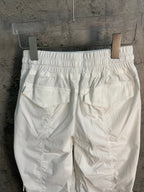 White cargo pants with elastic waistband and large front pockets, back view