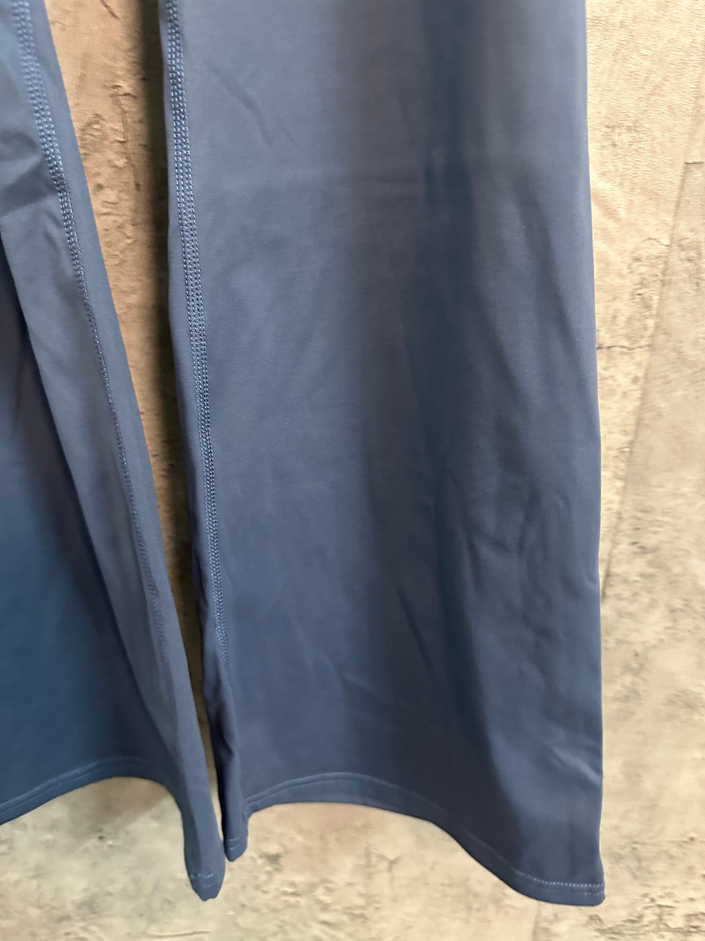 Blue athletic pants lower leg and hem with stitched edge and drape