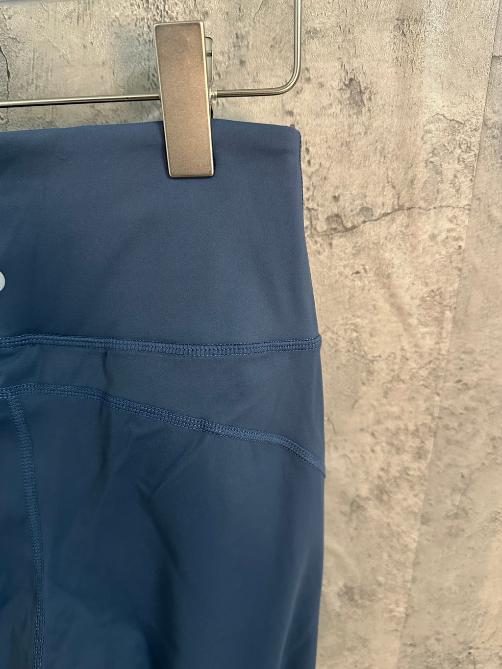Blue athletic pants side view with stitched pocket seam and curved panel