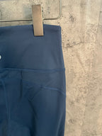 Blue athletic pants side view with stitched pocket seam and curved panel