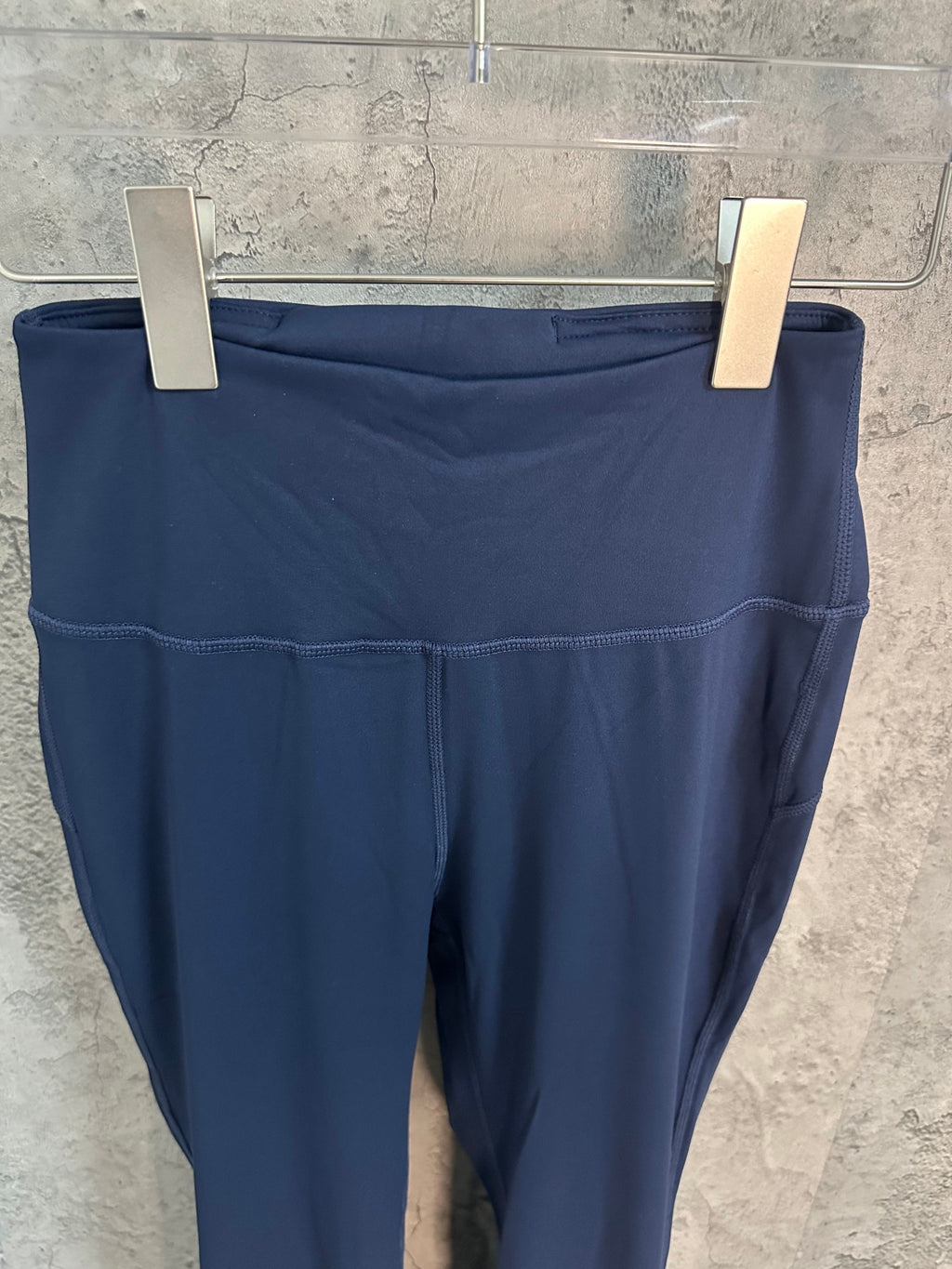 Navy athletic pants waistband and front seam detail, cropped view