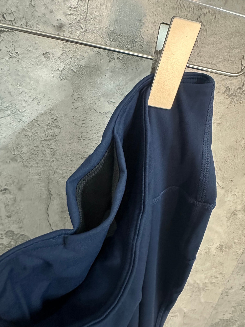 Navy athletic pants draped side view, waistband and inner seam visible