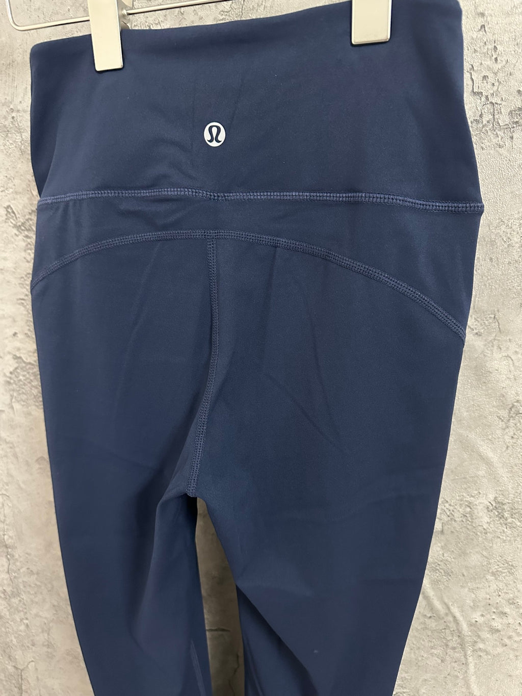 Navy athletic pants close-up of waistband logo and curved seam
