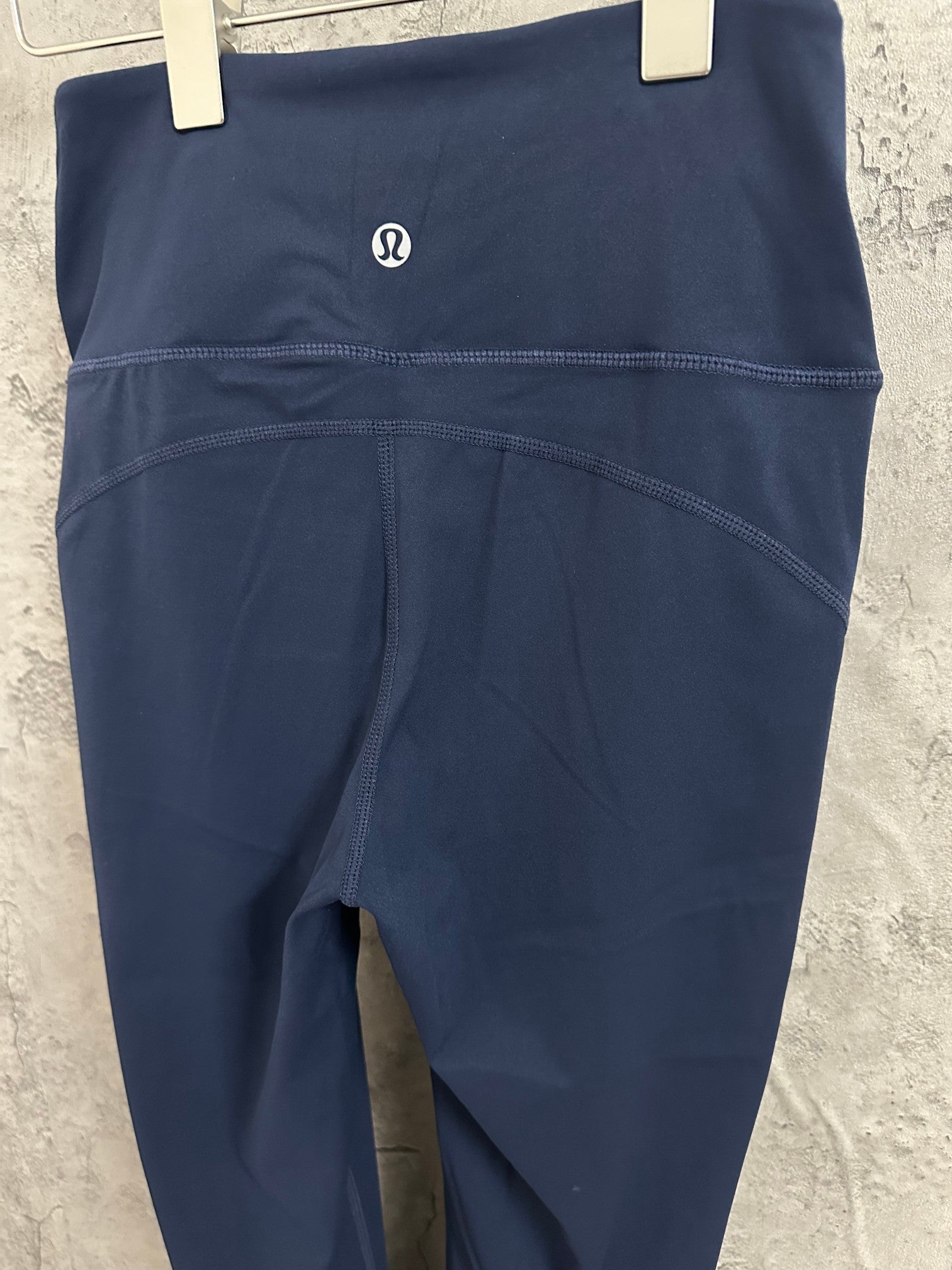 Navy athletic pants close-up of waistband logo and curved seam