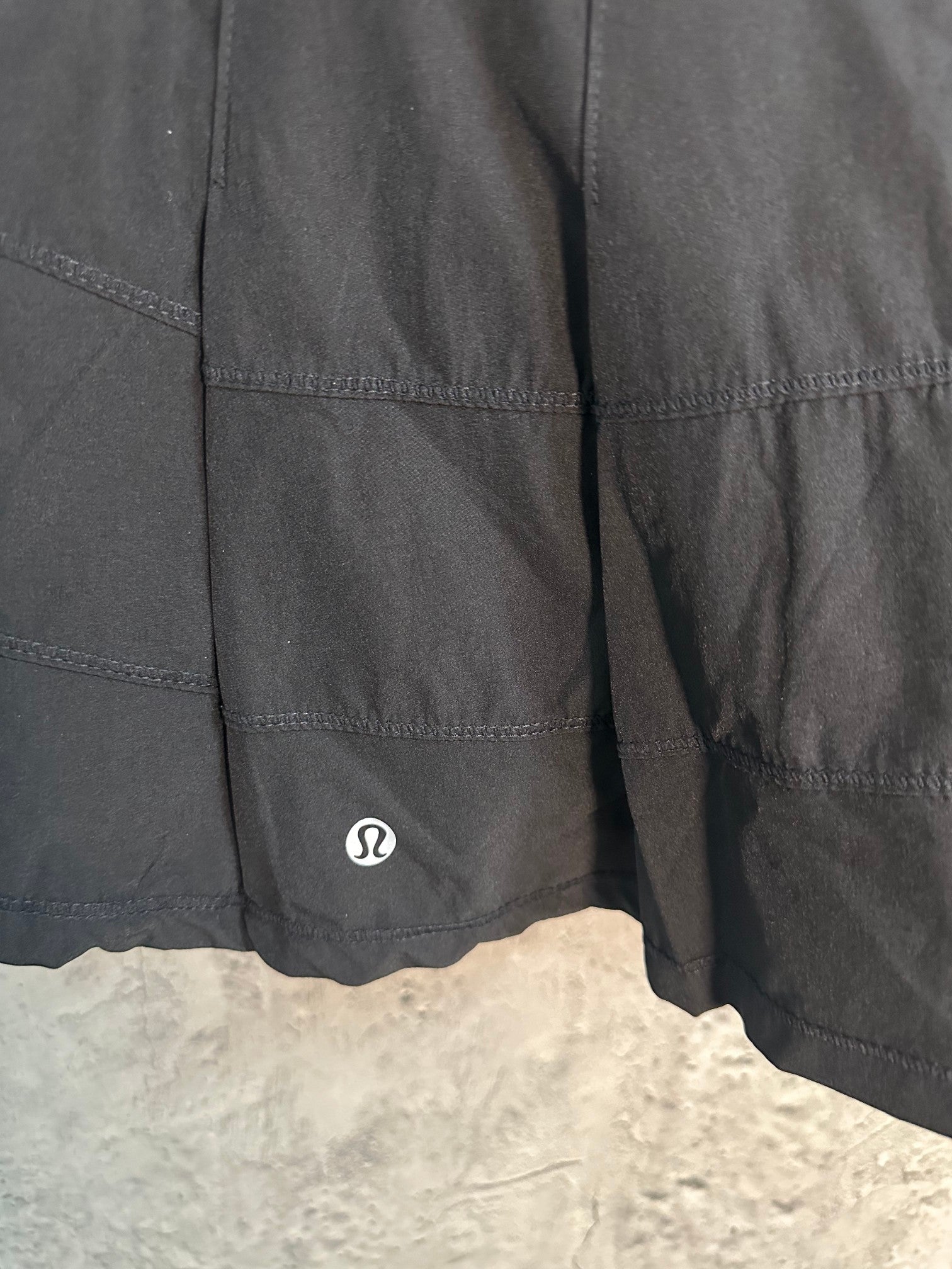 Black skort side panel with small circular logo and curved hem