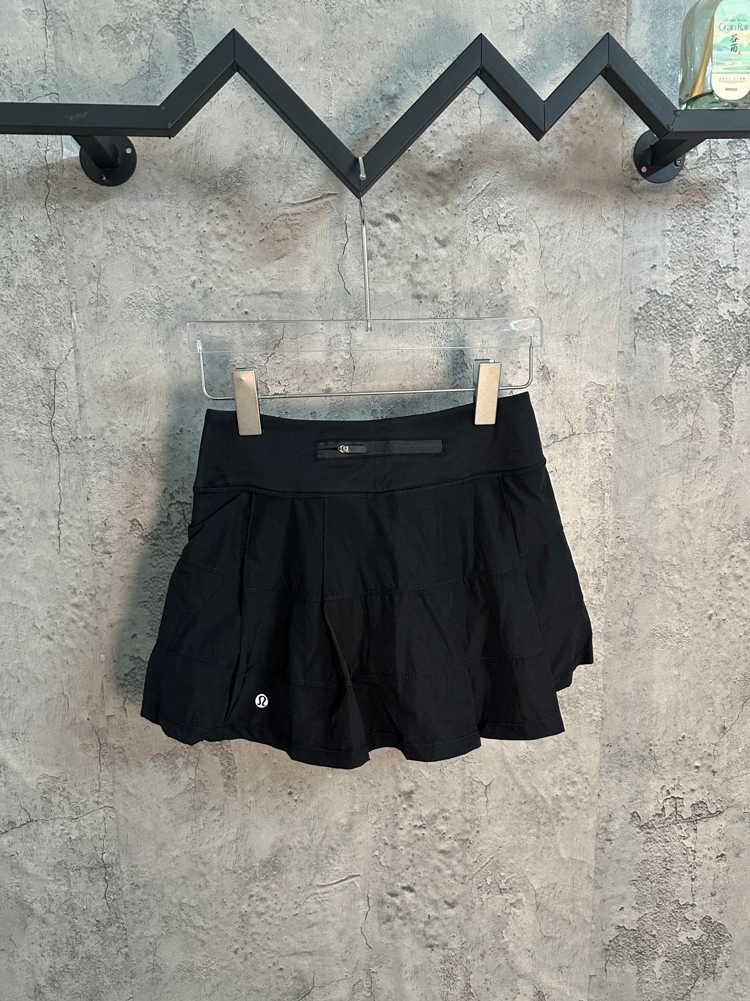 Black athletic skort with pleated front and concealed waistband pocket
