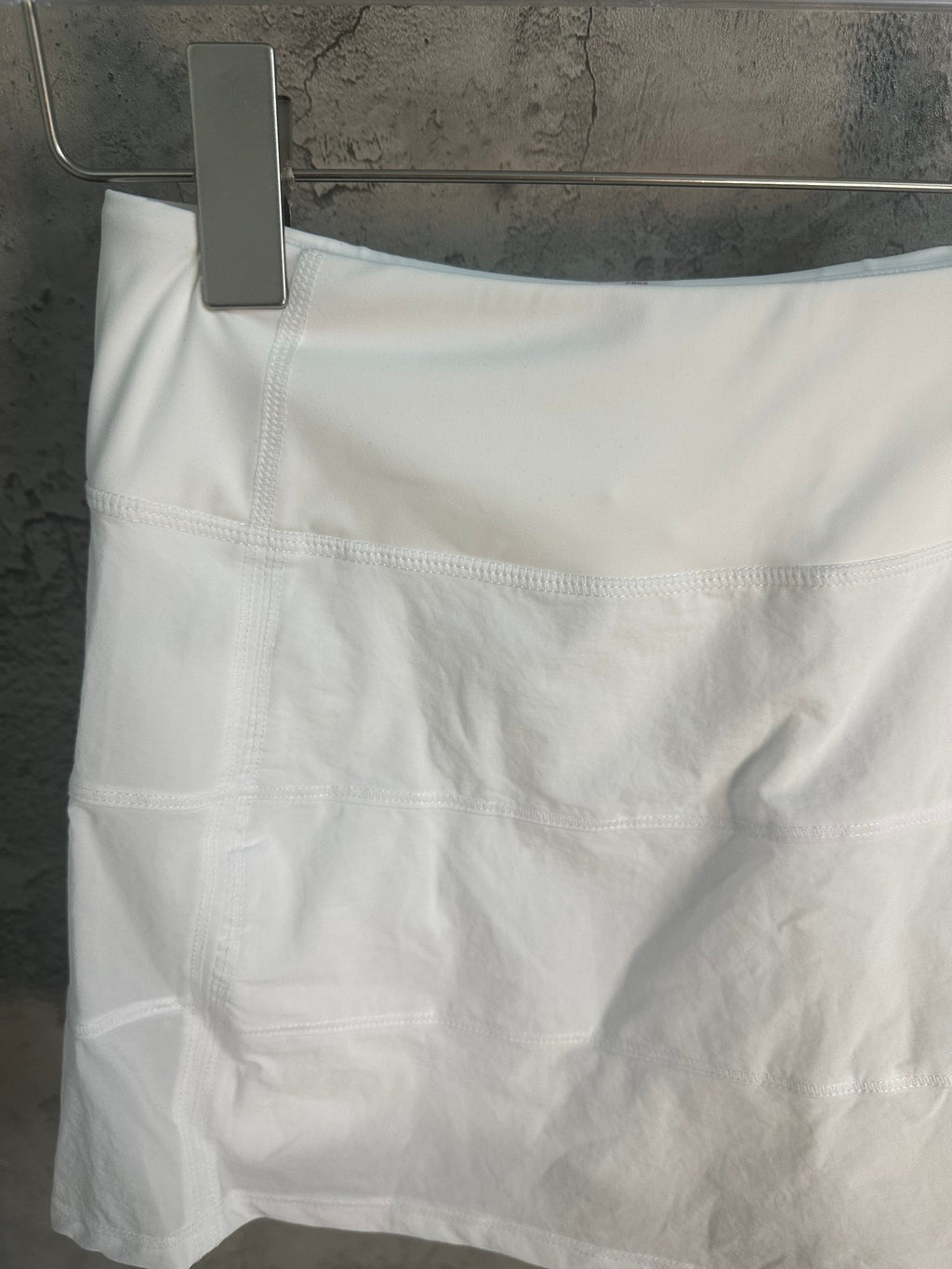 White skirt front with wide waistband seam and pleated panels