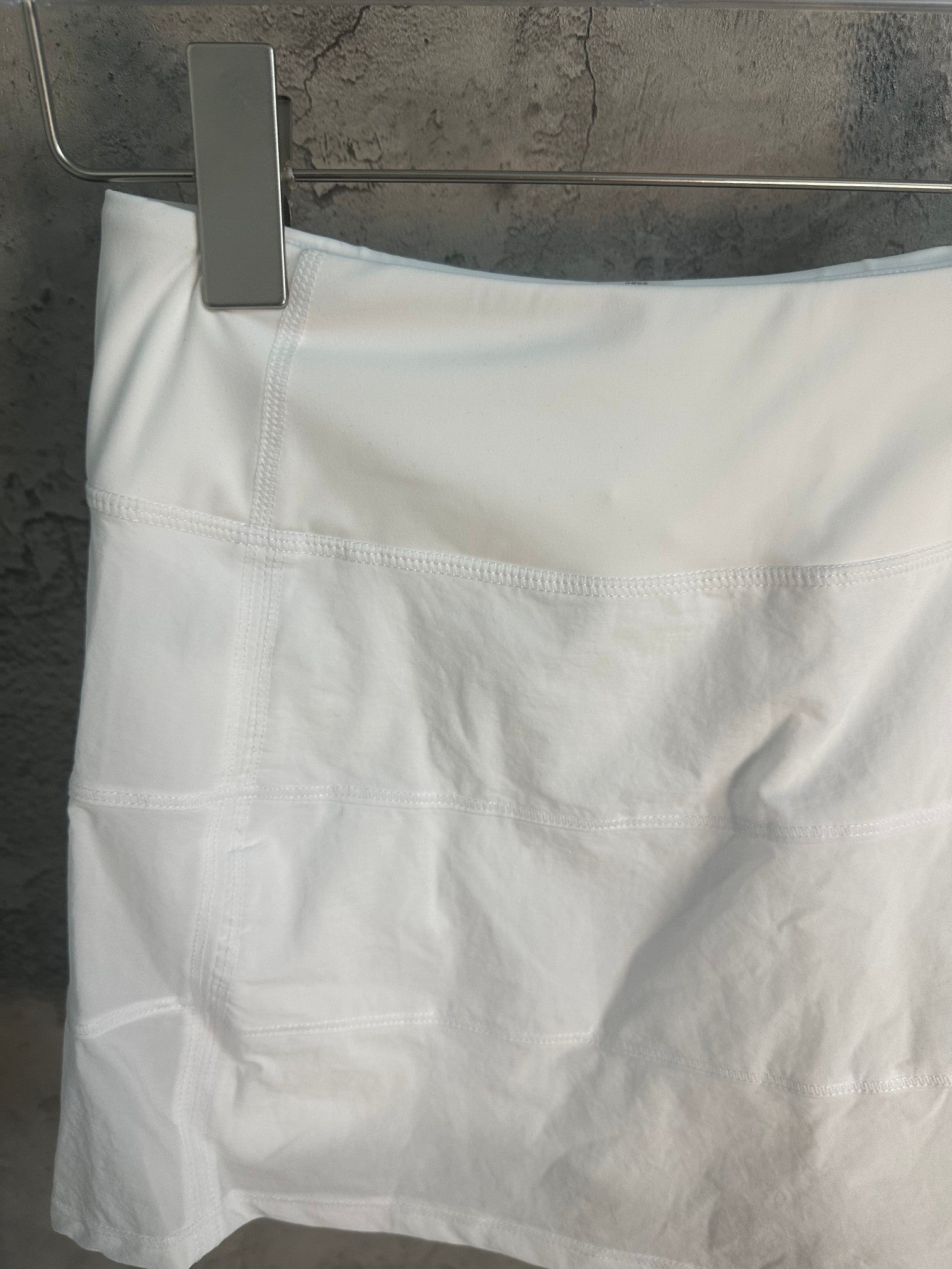 White skirt front with wide waistband seam and pleated panels