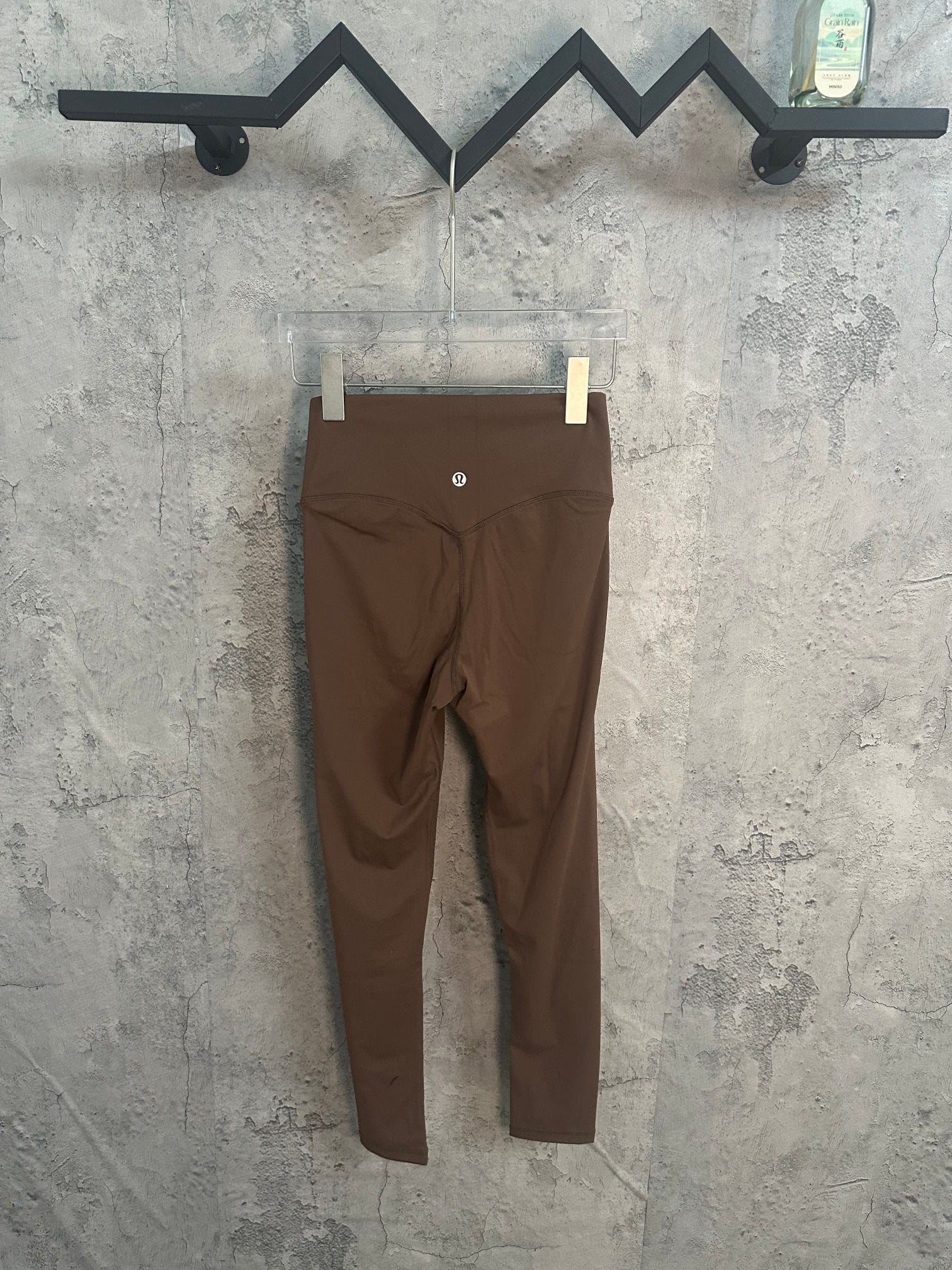 Brown pants on hanger, small logo at front waist