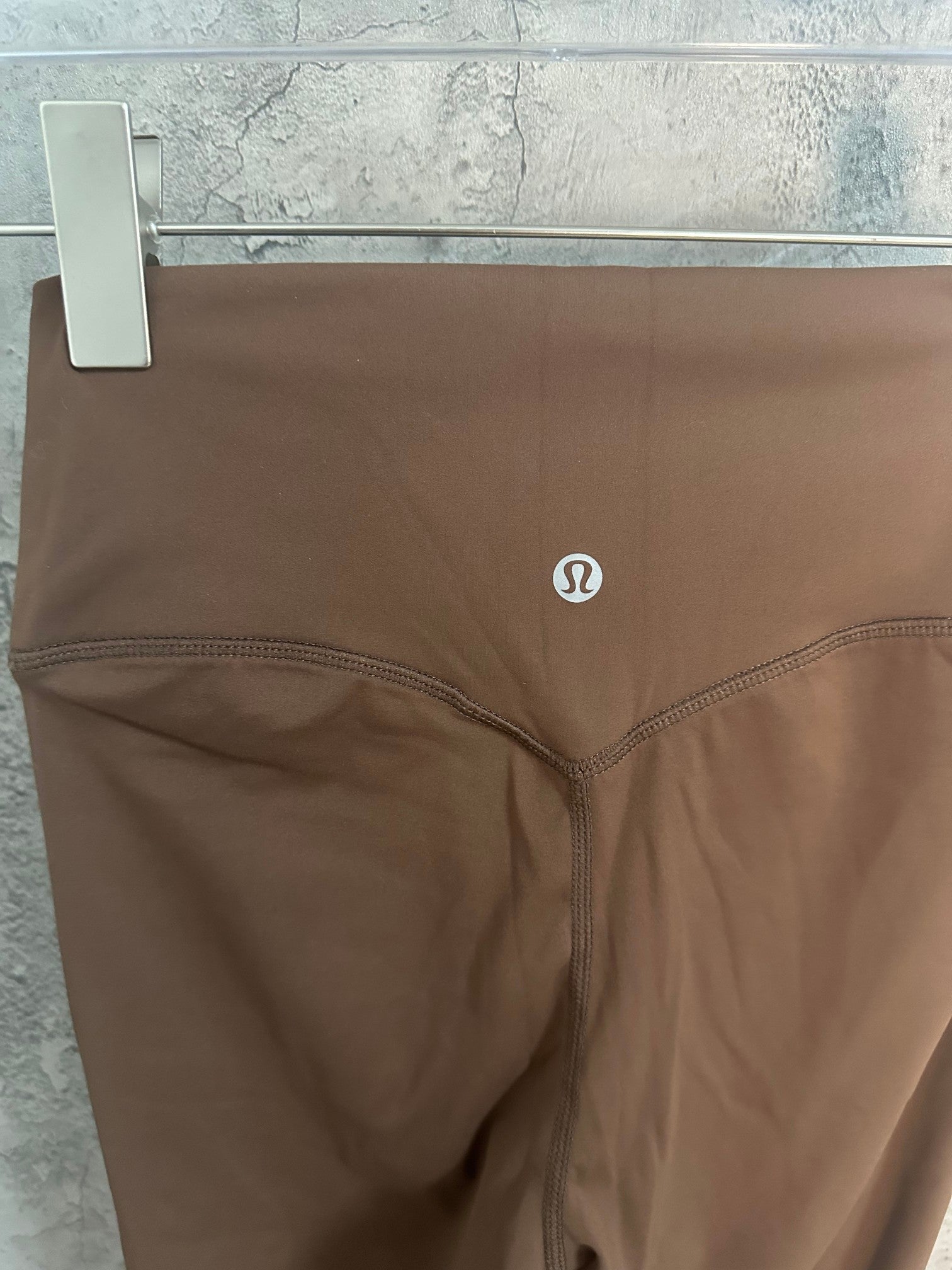 Brown leggings with Omega-style logo at hip