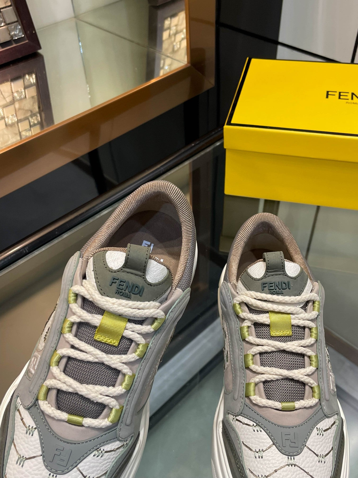 Gray unisex sneakers close-up with lime strap and FENDI logo details, white sole