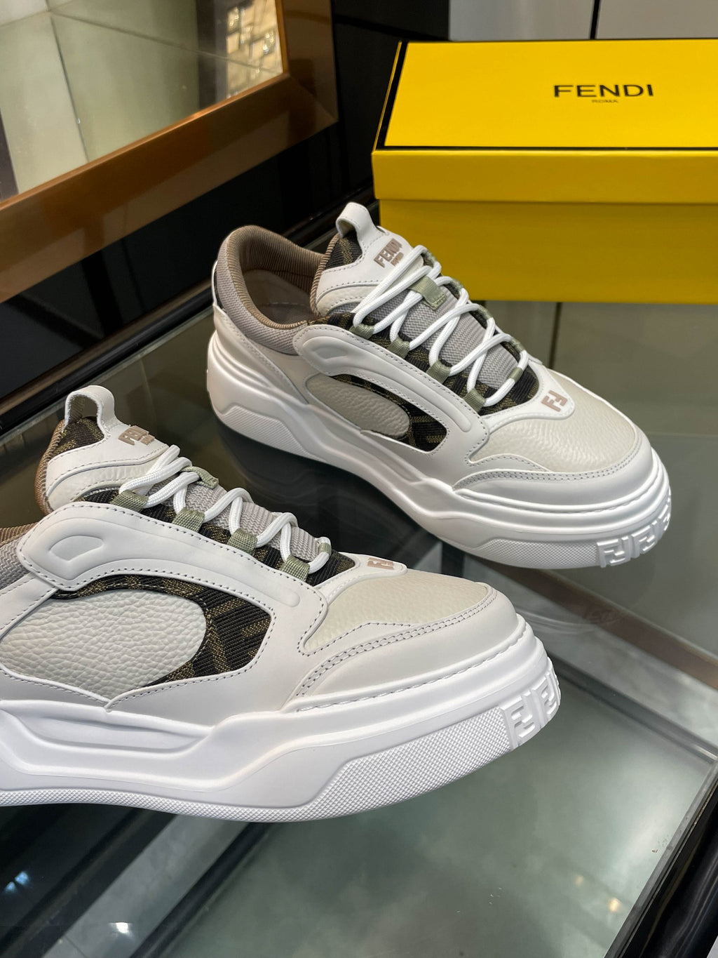 Two white and gray lace-up sneakers on display with chunky sole and logo accents