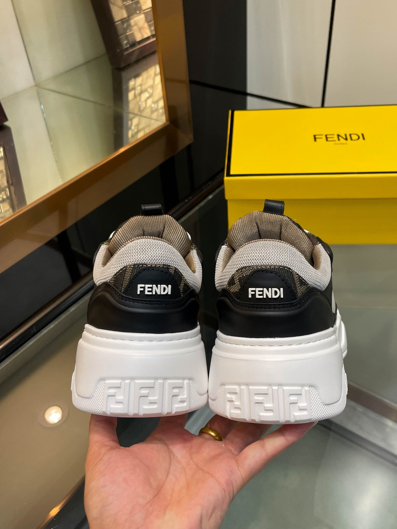 Back view of dark unisex sneakers with FENDI heel tabs and chunky white tread