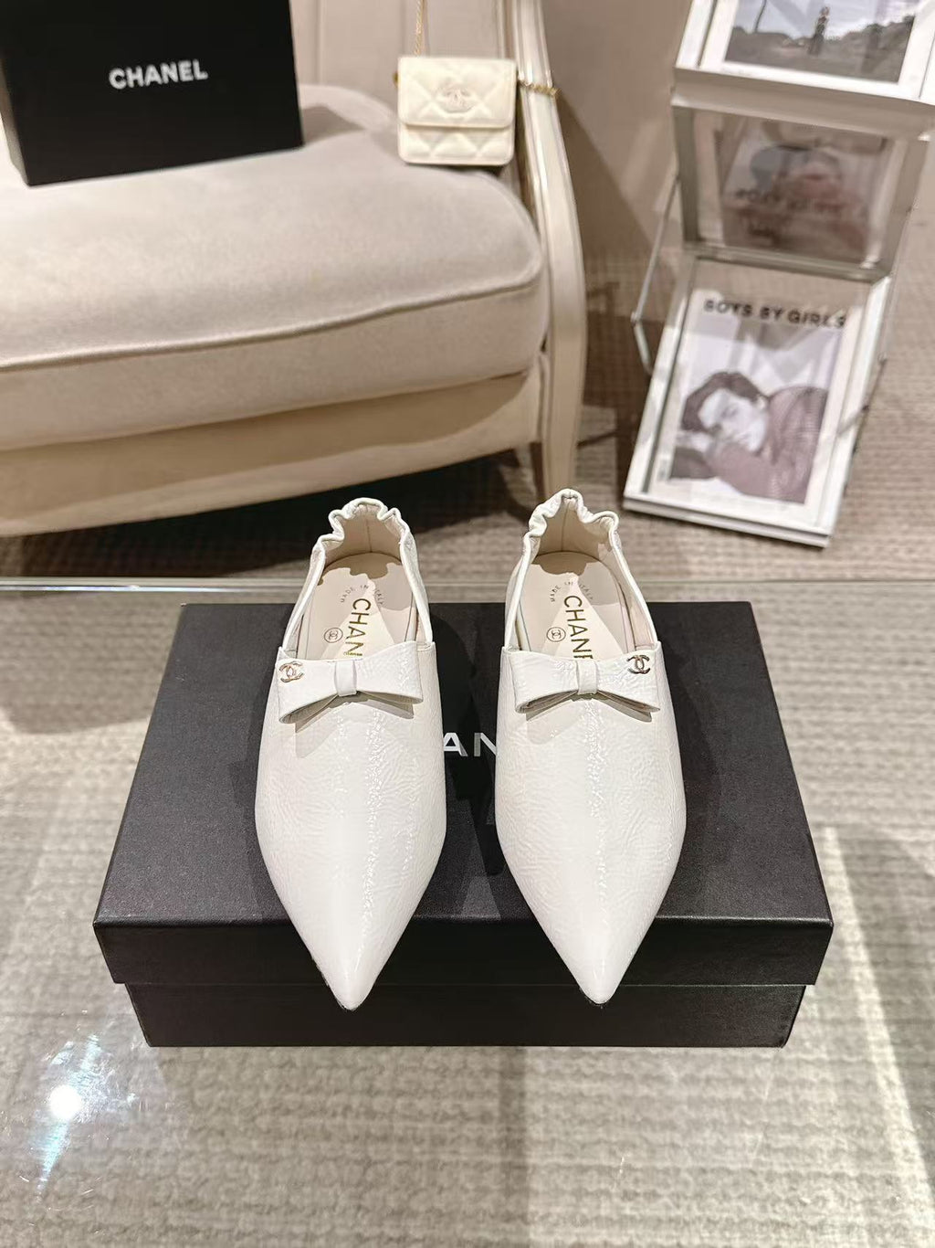 Pair of white pointed-toe flats with bow strap and Chanel logo on insole