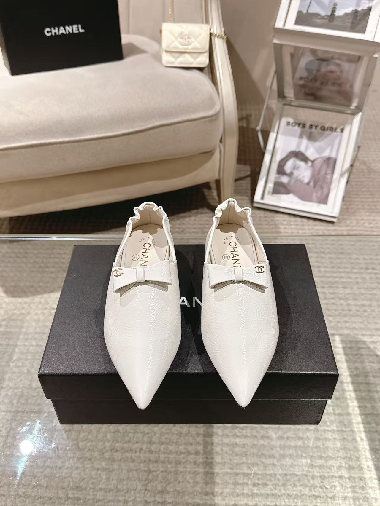 Pair of white pointed-toe flats with bow strap and Chanel logo on insole