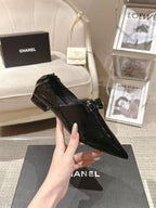 Black patent leather ladies pointed-toe shoes with bow detail and low block heel