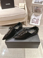 Black patent leather ladies pointed-toe slip-on shoes on a box, bow-adorned