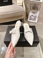 White Chanel flats with bow strap, front view showing logo insole