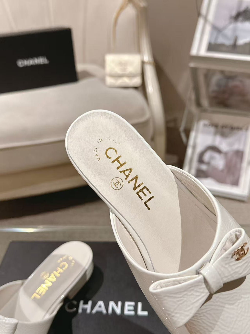 White Chanel mule-style flats with bow strap, branded insole