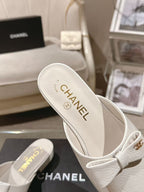 White Chanel mule-style flats with bow strap, branded insole