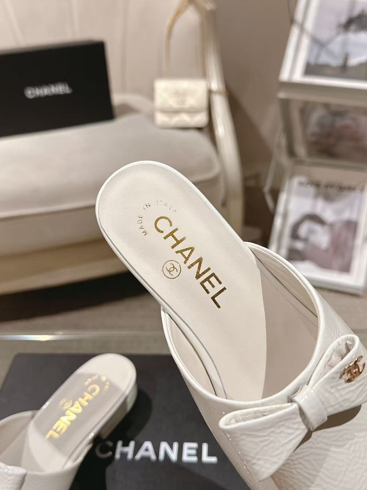 White Chanel mule-style flats with bow strap, branded insole
