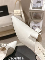 White pointed-toe Chanel flat, side profile with bow tie detail