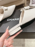 White pointed-toe Chanel flats with bow strap and low heel
