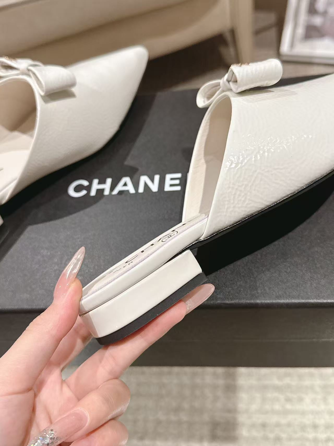 White pointed-toe Chanel flats with bow strap and low heel