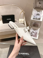 White Chanel flats with bow strap and slim low heel, angled view
